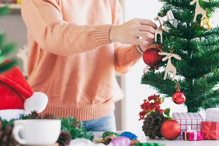 woman decorating a mini christmas tree on her desk