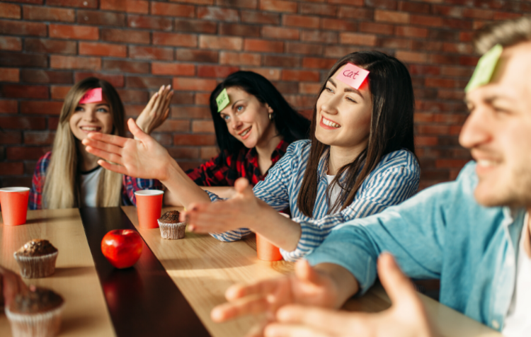 Four people with sticky notes on their heads playing a game