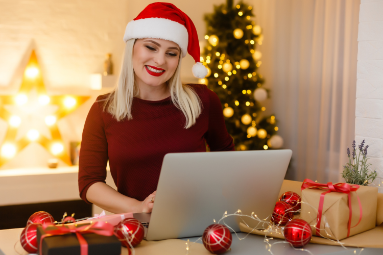 woman in a santa hat planning a holiday party on her laptop