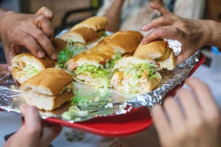 people enjoying muffaletta sandwiches on a food tour