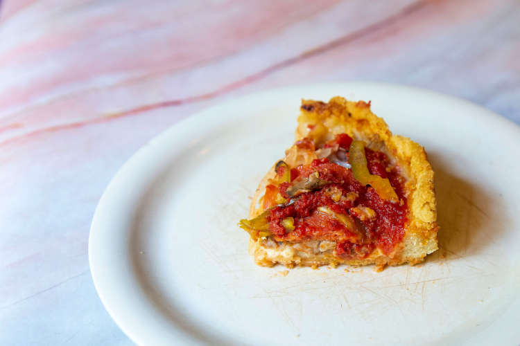 slice of deep dish pizza on a chicago pizza tour