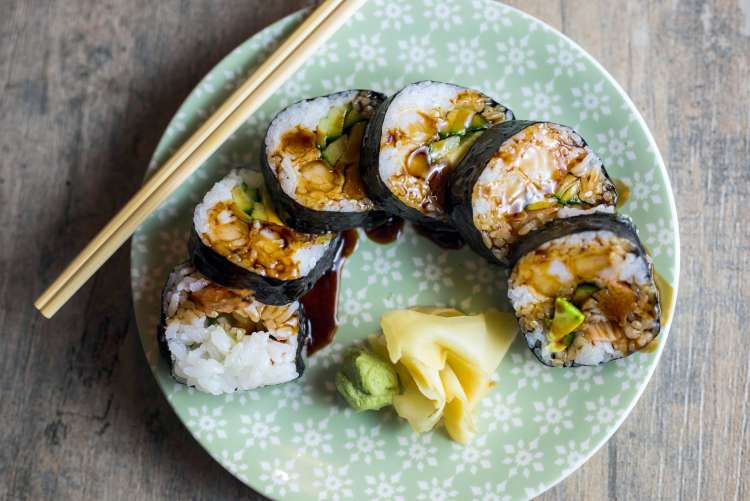 maki sushi on a plate with chopsticks, ginger and wasabi