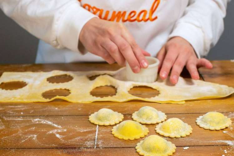 a chef in a Cozymeal apron cutting out gnocchi