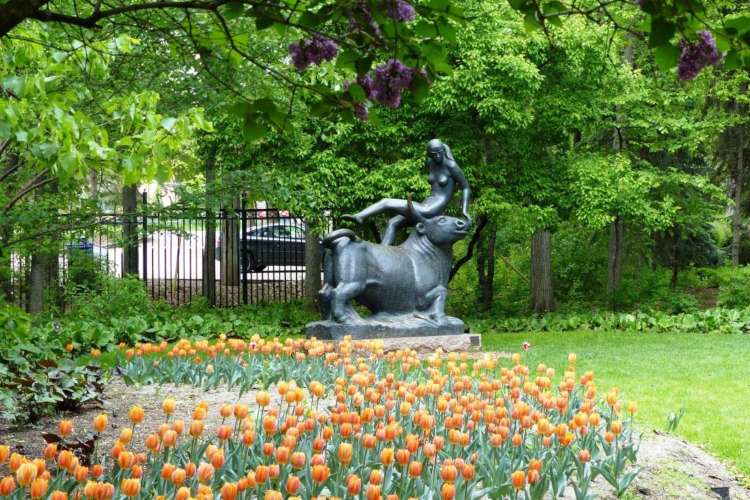 a sculpture of a woman on a bull in a garden