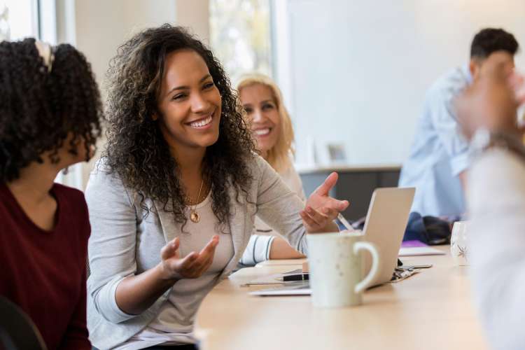 a woman presenting at a table with her co-workers