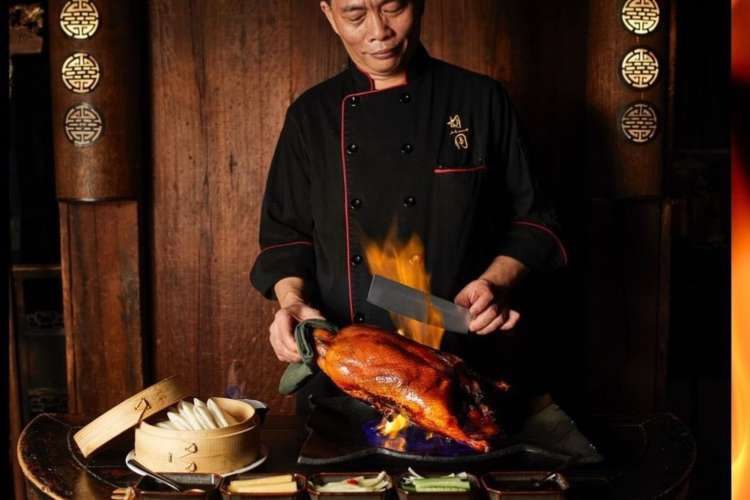 a chef preparing a flaming duck at a table