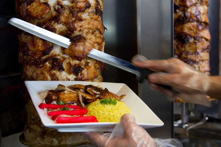 meat being sliced off a skewer for shawarma 