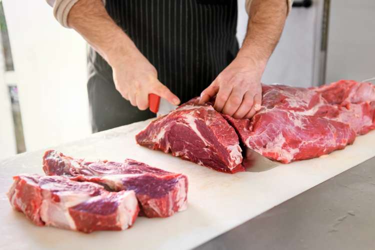 butcher slicing chuck steaks