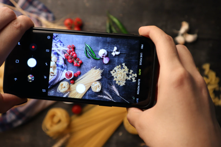 view through the screen of someone photographing a tableau of pasta and vegetables