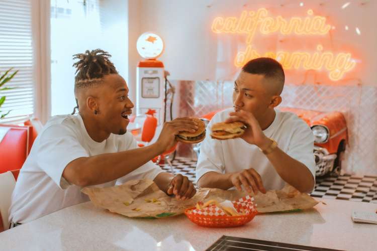 two men have a hamburger in a colorful diner