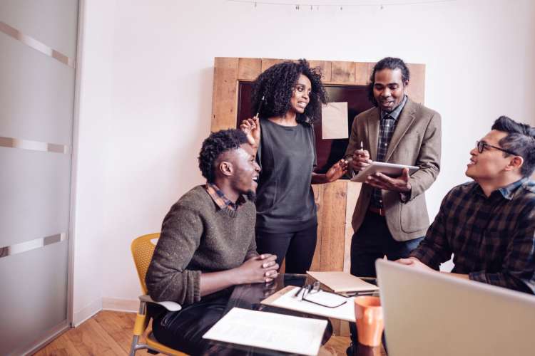 a multi-ethnic group chats together in a bright office