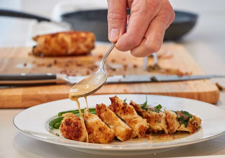 chef plating breaded chicken breast with green beans