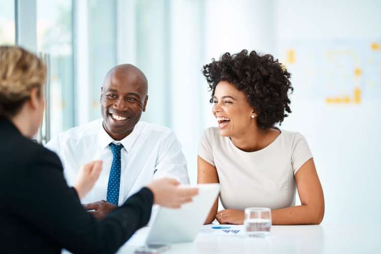 three happy, smiling coworkers reviewing documents at a table