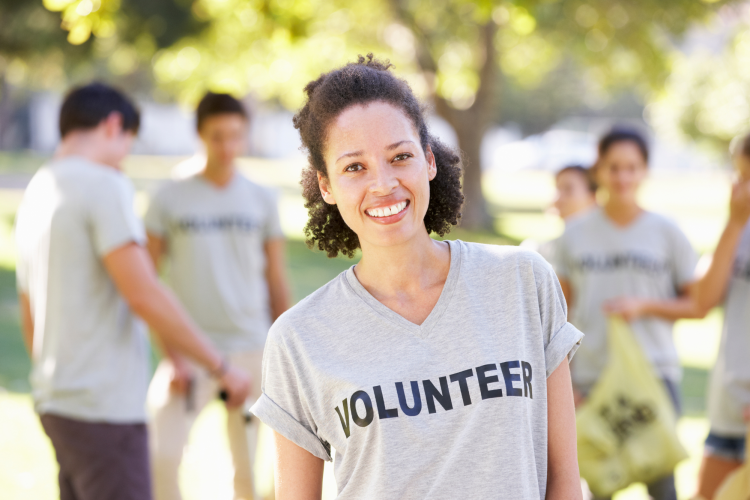 A woman smiling while volunteering with people in the background