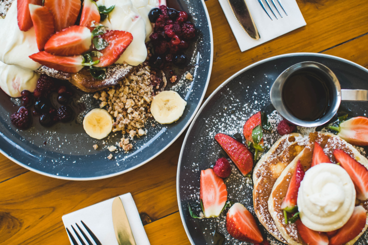 pancakes with whipped cream and berries on a table for brunch