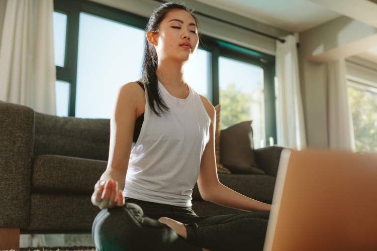 young woman meditating with her laptop