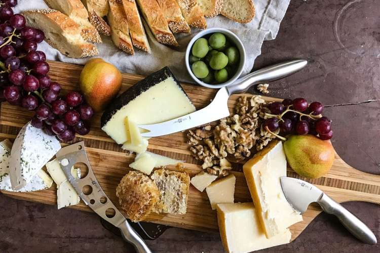 A Zwilling 3-Pc Cheese Knife Set on a cheese board