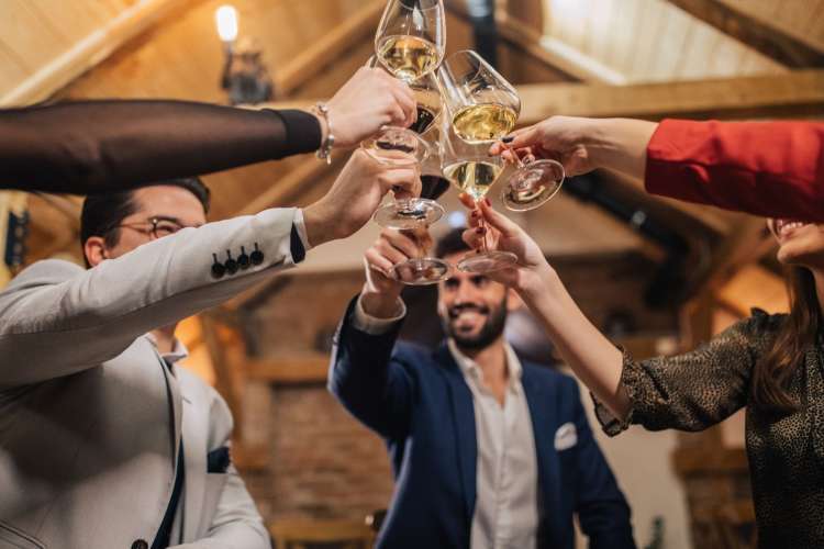 a group of smiling friends toasting with glasses of white wine