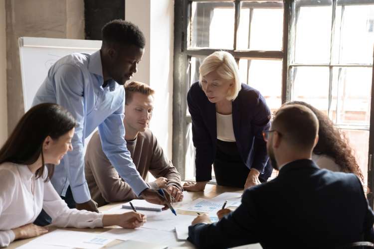 a diverse group of professionals pore over charts 