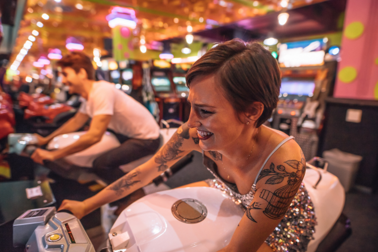 young man and woman riding arcade motorcycles in a gaming parlor