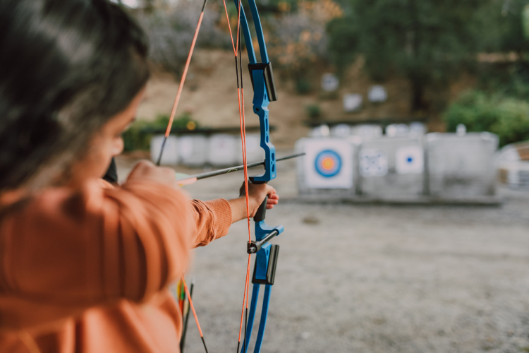 woman taking aim with bow and arrow