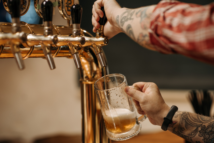 man pouring a beer from the taps inside a brewery