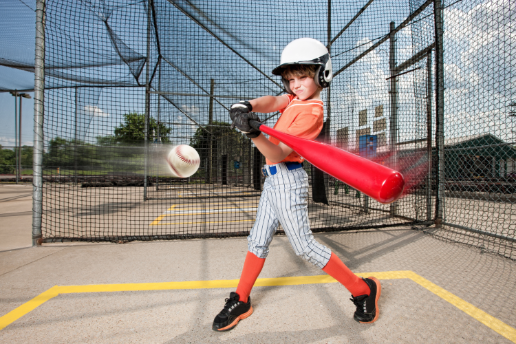 kid taking a swing at the batting cages