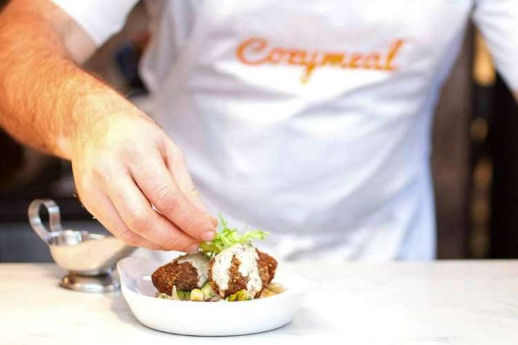 a chef garnishing a dish of meatballs