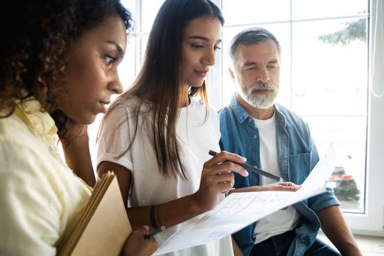 a woman points out something on a paper while two coworkers look on