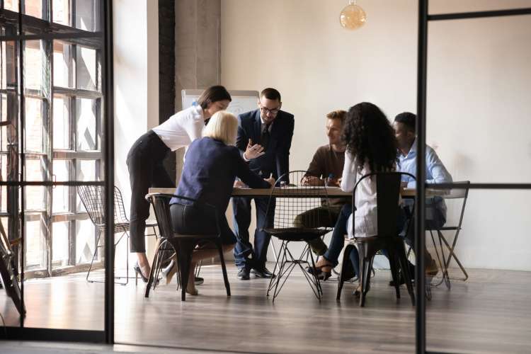 six racially diverse coworkers gathered around a table in discussion