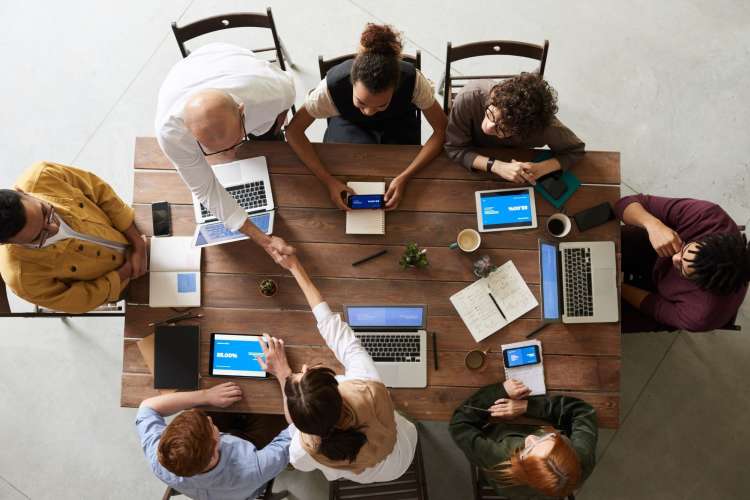 view from above of eight professionals around a table with laptops