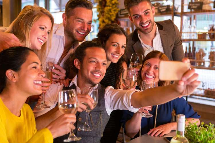 a group of coworkers taking a selfie at a happy hour in a bistro