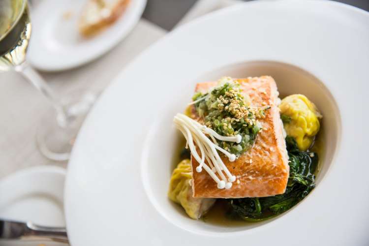 plated salmon with braised greens, enoki mushrooms and white wine