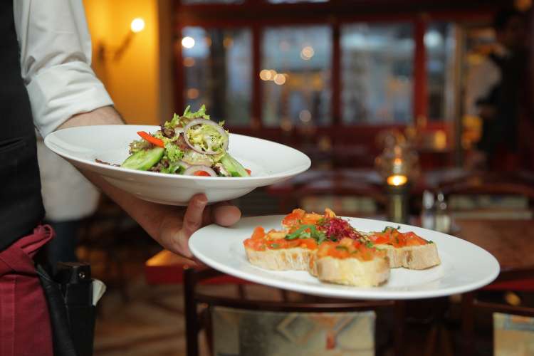 waitress carrying plates of food in a gourmet restaurant