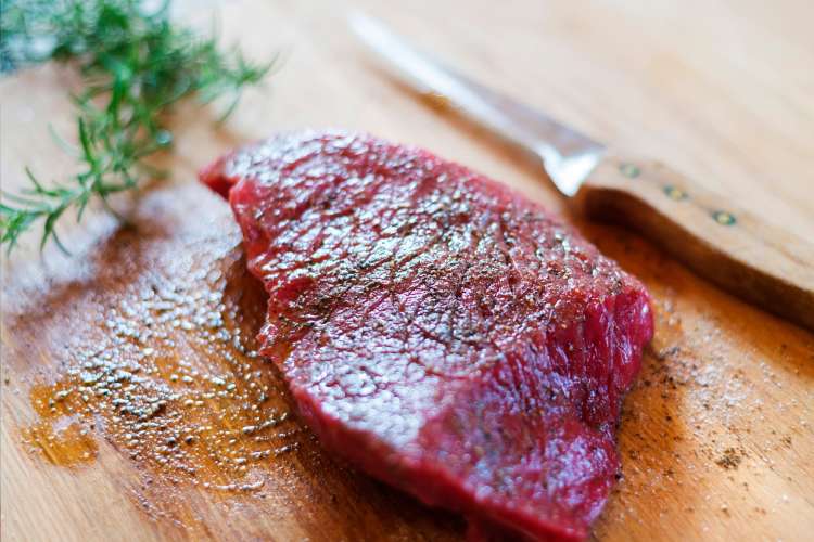 boning knife with cut of raw steak and rosemary