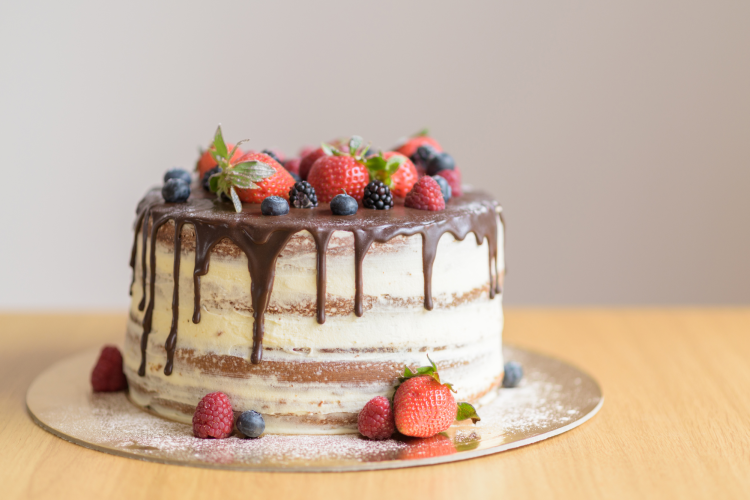 A cake, which is a popular dessert, covered in chocolate frosting and topped with fruits
