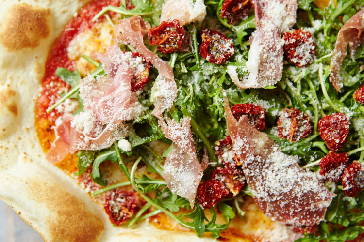 pizza topped with arugula and prosciutto