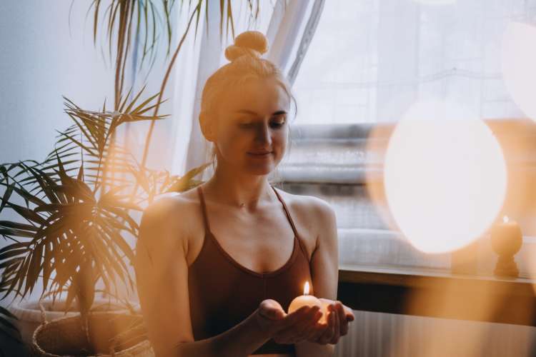 young woman lighting a candle to do yoga