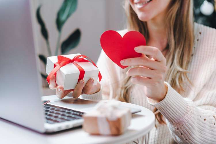 woman opening a care package gift on video chat