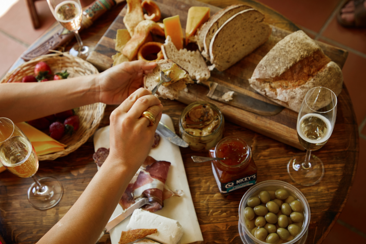 woman spreading jam on bread over a charcuterie board