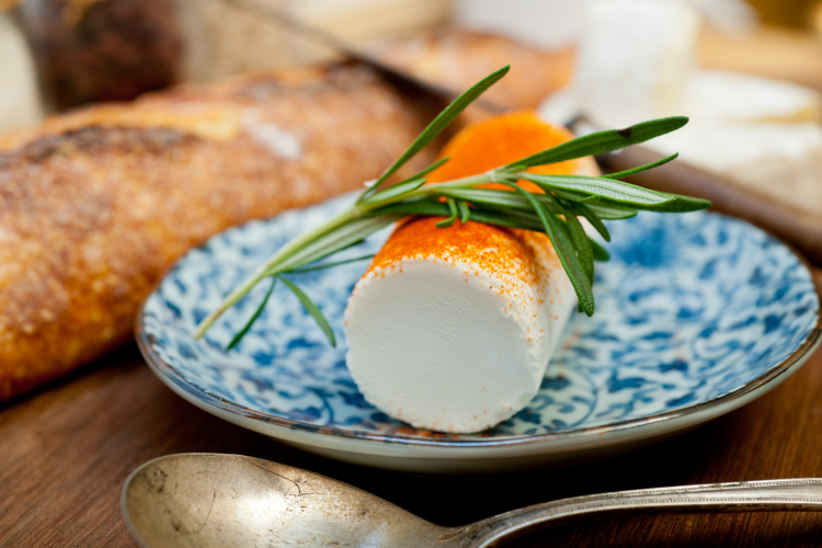 A log of goat cheese on a white and blue patterned plate