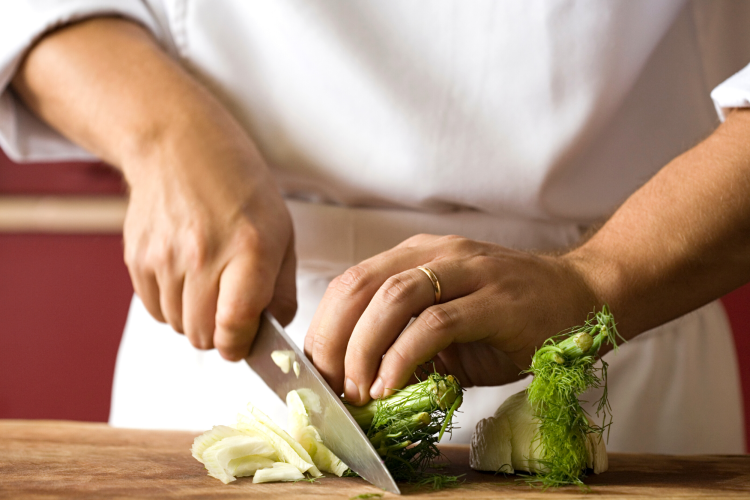 chef chopping a bulb of fennel on a cutting board