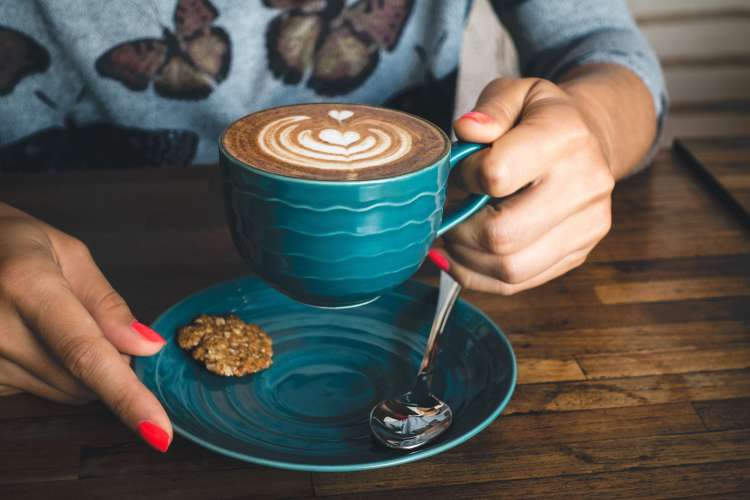 woman enjoying a latte with a baked treat