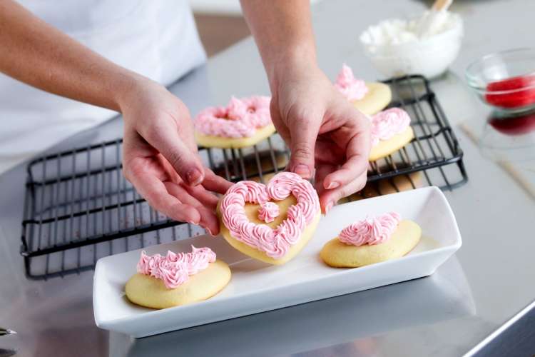 woman making heart shaped frosted cookies