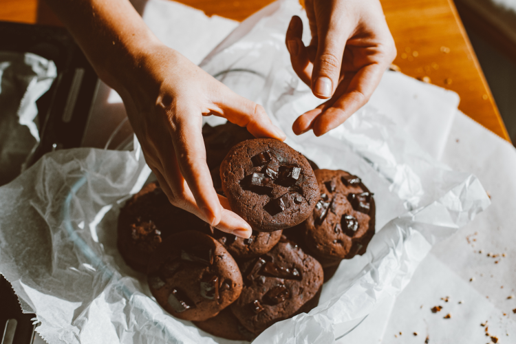 Two hands grabbing chocolate cookies with chocolate chips