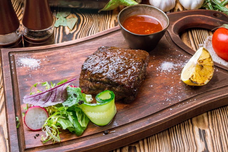 denver steak on a cutting board with vegetables