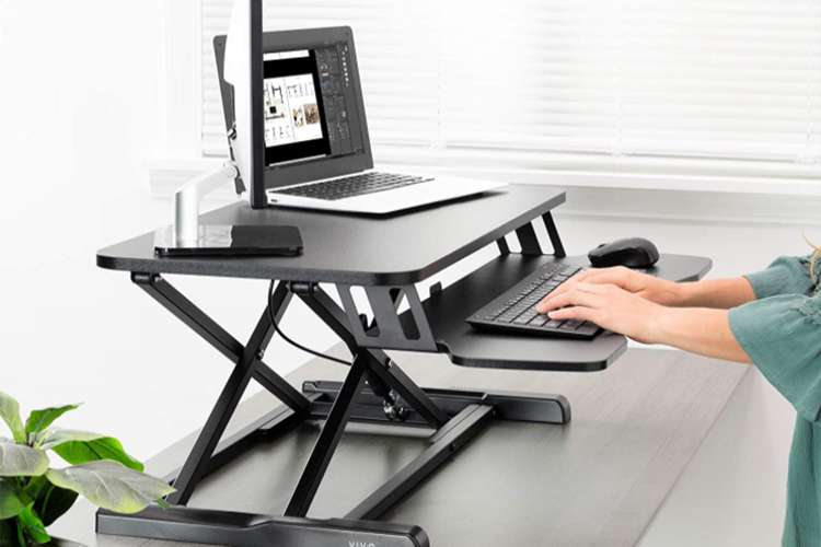 woman working on a computer with a desk riser