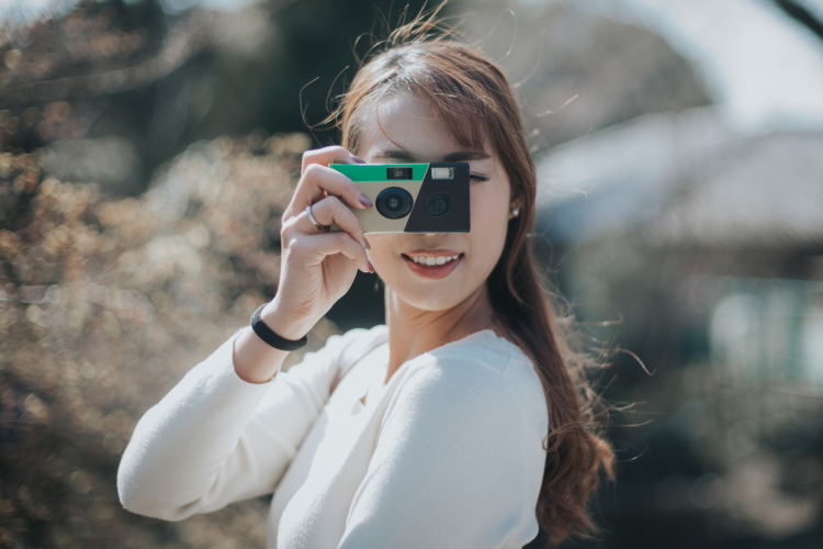 young woman holding a disposable camera