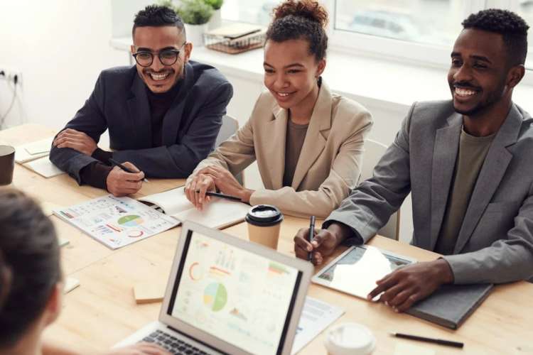 Suited employees examining charts and smiling together