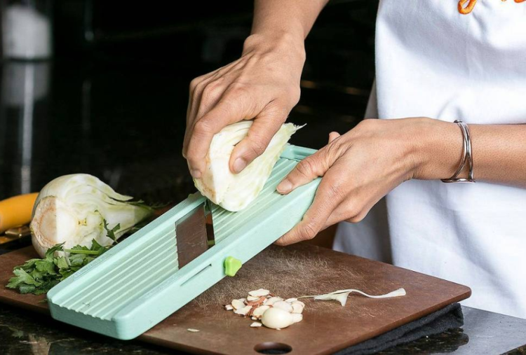 chef's hand slicing fennel on a mandoline